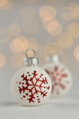 White christmas balls with red snowflakes on a light background with yellow bokeh.Christmas and New Year winter festive background