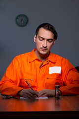 Young convict man sitting in dark room