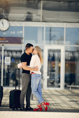 Couple in a airport. Beautiful blonde in a white jacket. Man in a black t-shirt