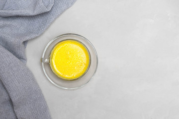 Obraz na płótnie Canvas Warm homemade turmeric golden milk in a glass cup on grey neutral background