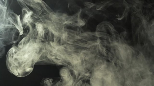 Smoke flies through the frame on a black background. Good footage for effects and transitions.