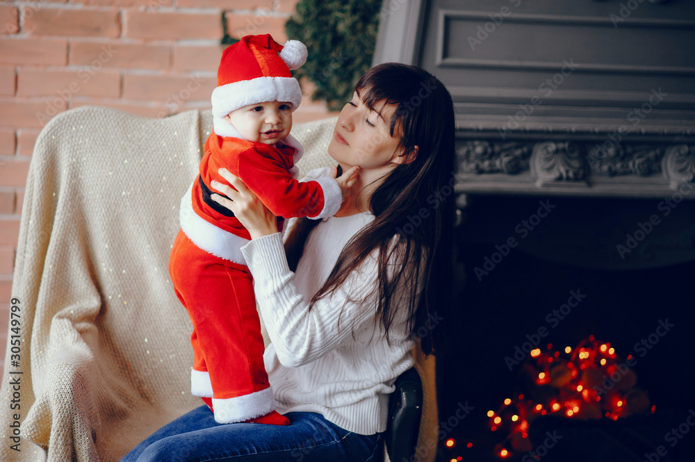 Poster Beautiful mother in a white sweater. Family in a christmas decorations. Little boy in a santa costume