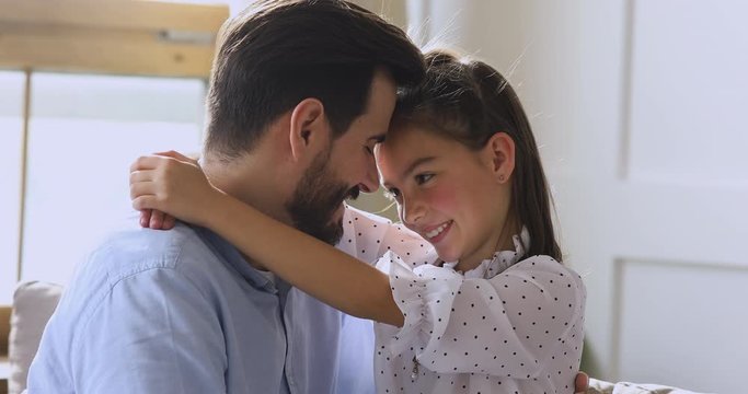 Affectionate little child daughter hugging dad bonding sitting on sofa