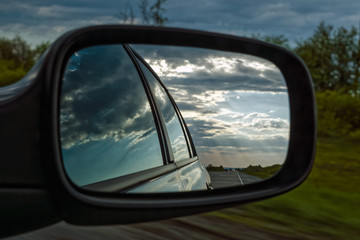 Fototapeta na wymiar view from a car mirror on a stormy sky