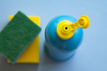 a bottle of liquid cleaner and a washcloth lie on a blue background,