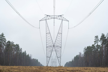 The high-voltage line tower on a clearing in the forest. Autumn, early morning.