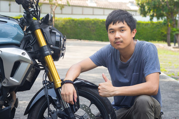 Obraz premium Attractive guy in t-shirt is looking at camera and smiling while sitting on the motorcycle. Motorcycle smile.