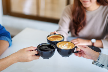 Closeup image of people enjoyed drinking and clinking coffee cups together on the table in cafe