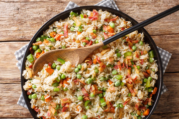 Tasty rice cooked with vegetables and bacon close-up in a plate. horizontal top view