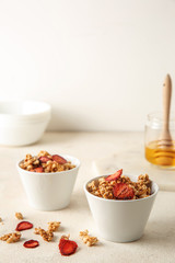 Bowls with tasty granola and berries on white table