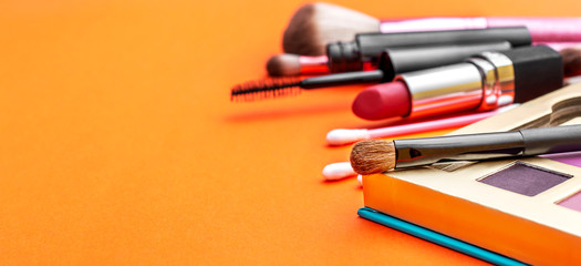 Makeup accessories on bright orange background.