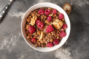 Bowl with tasty granola and berries on grunge background
