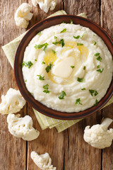 mashed cauliflower with butter and parsley close-up on a plate. Vertical top view