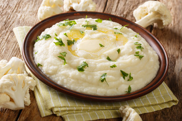 hot side dish of cauliflower puree with butter and parsley close-up on a plate on the table. horizontal