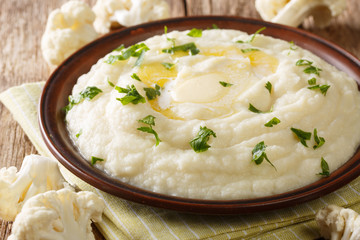 Homemade mashed cauliflower with butter and parsley close-up on a plate on the table. horizontal