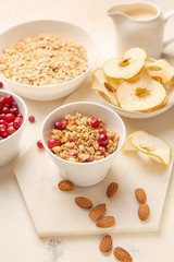 Tasty granola with fruits and nuts on light background