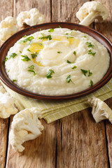 Dietary delicious cauliflower puree with butter and parsley close-up on a plate. vertical
