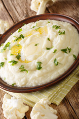 mashed cauliflower with butter and parsley close-up on a plate on the table. vertical