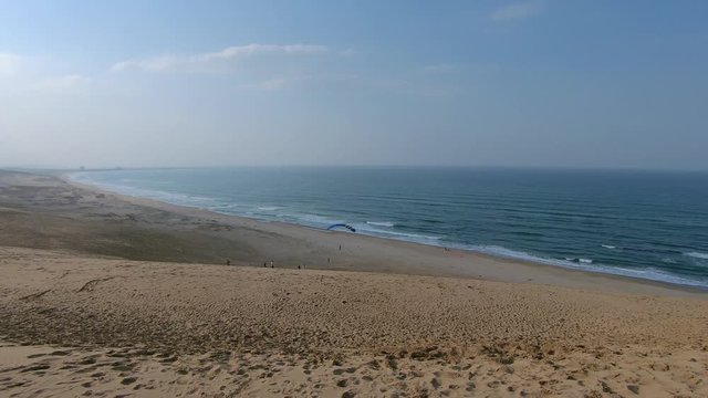Parachutist flying along sandy beach, Tottori Sand Dunes, Japan, wide shot
