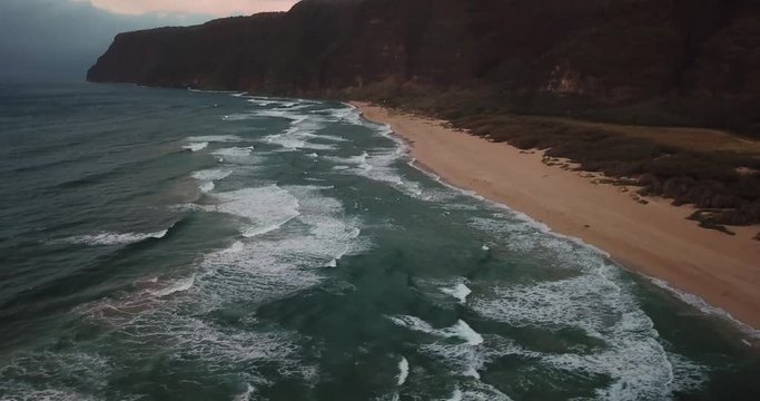 Dynamic drone shot of beach and ocean at sunset in Kauai, Hawaii