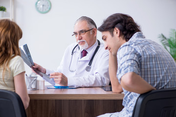 Young couple visiting old male doctor