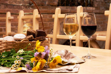 Still life with two glasses with red and white wine on wooden table in the old vintage wine cellar from red brick