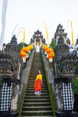 Bottom-up view of the Balinese temple decorated for the holiday Galungan. Woman standind on the stairs. Bali, Indonesia. Vertical orientation