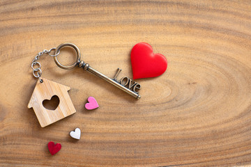 House key in heart shape with home keyring on old wood background decorated with mini heart - 305155758