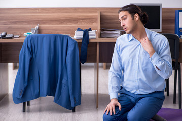 Young handsome businessman doing exercises at workplace