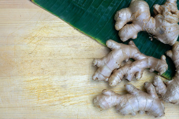 Fresh ginger root and ginger sliced on green leaf background on wood table background, healthy...