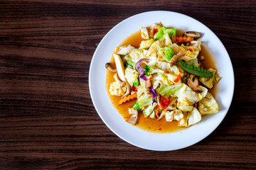 Stir fried mixed vegetable with crispy pork, add chilies in a white dish.