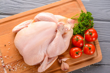 Raw chicken with spices and tomato on wooden background