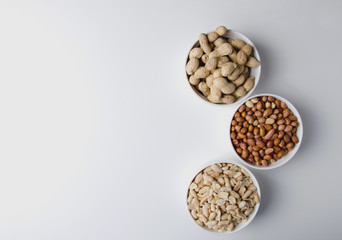 Three kinds of nuts in a white bowl on a white background. Horizontal orientation