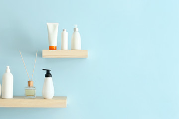 Shelves with cosmetic products hanging on color wall
