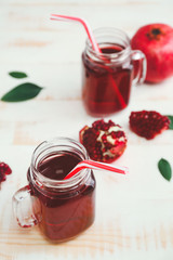 Mason jars of tasty pomegranate juice on table