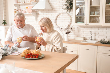 Happy mature couple having breakfast on Christmas eve in kitchen