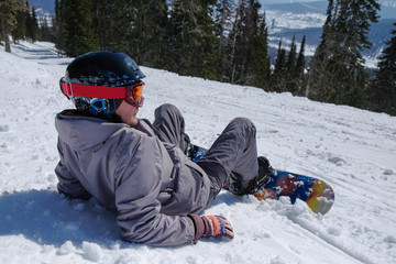 Young snowboarder riding in the mountains on a snowboard.