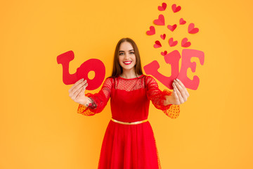 Beautiful young woman with word LOVE and hearts on color background. Valentine's Day celebration