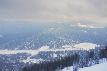 Winter landscape in Sheregesh. Frozen snow on trees. Frozen trees on a background of blue cloudy sky. A lot of snow fell in the winter cold in the mountains. Sunrise in the mountains
