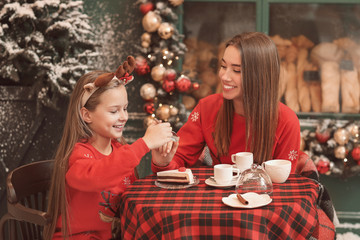Fototapeta na wymiar Happy mother with daughter in outdoor cafe on Christmas eve