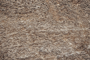 Brown old wall close-up from a block of limestone in the style of grunge. Vintage texture of natural stone. Background for the subject flat lay. Concept of construction and interior design. Copy space