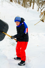 Cleaning snow in winter, the boy shovels snow.