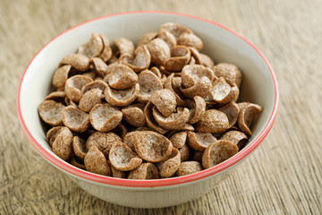 Cereals breakfast cocoa flavor in bowl on wooden backdrop