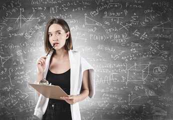 Fototapeta premium Thoughtful woman with clipboard studying