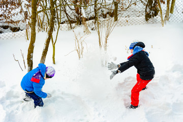 Two brothers playing snowballs near their home.