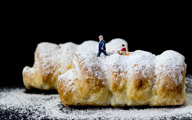man pulling sled with child on pastry with icing sugar 