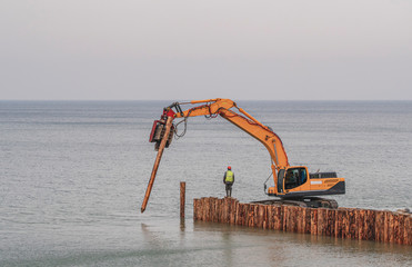 A special technique sets up wooden logs for a breakwater