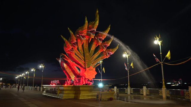 A seven headed Naga staue spouting water and illuminated at nght-time in Sri Chiang Northern Thailand.