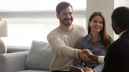 Happy Caucasian clients handshake male consultant greeting