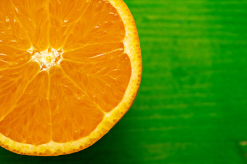 closeup of a half ripe orange on green ground